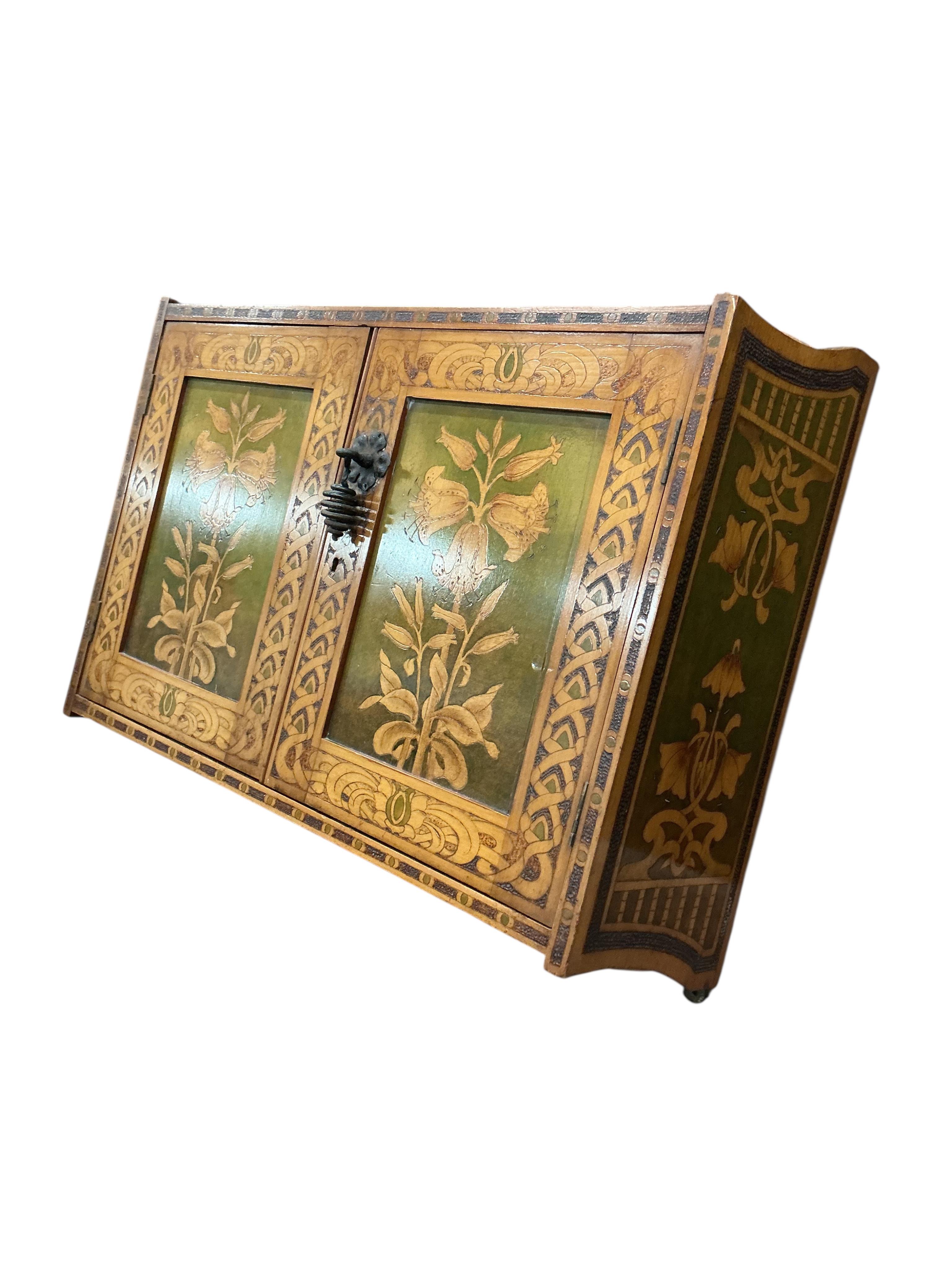 An Art Nouveau poker work two door wall cabinet, width 61cm, depth 21cm, height 52cm